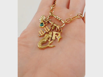 A demonstration of how to create a personalised gold charm necklace with an oval carabiner clasp and a collection of charms, made from tarnish proof waterproof surgical steel
